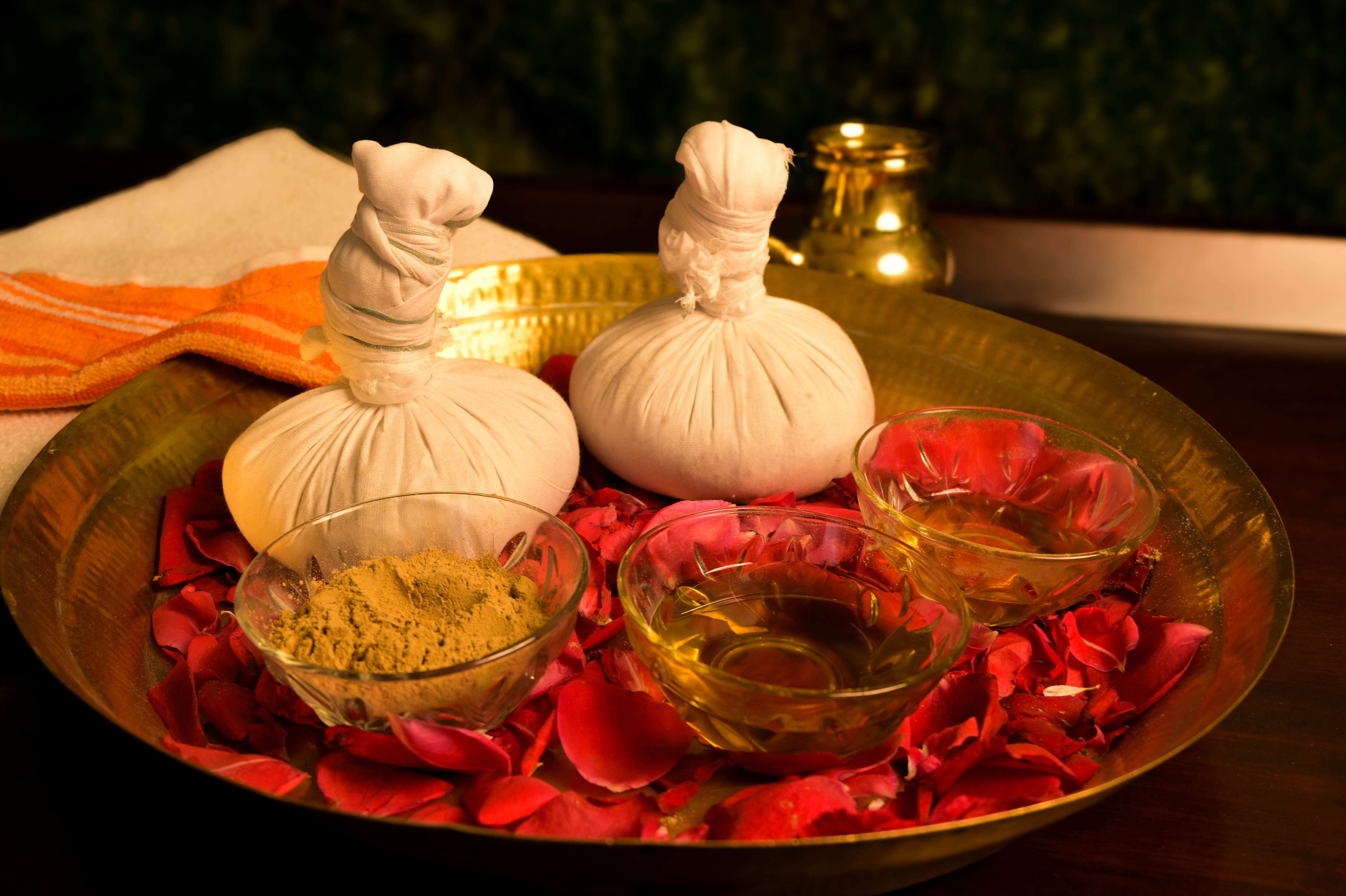 Ayurveda treatment preparation with potlis, oil, and herbal powder.